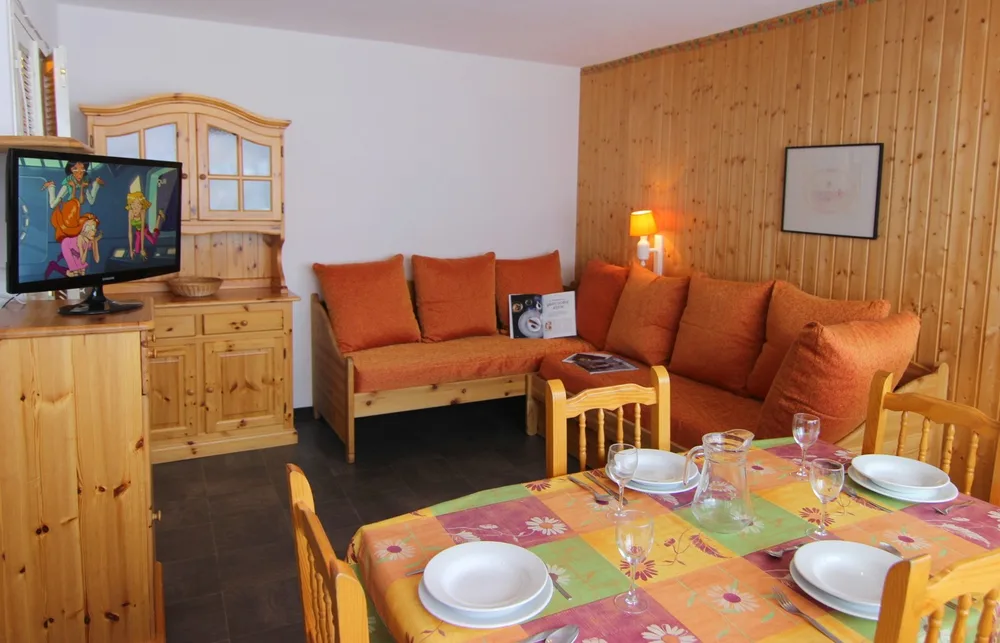 Dnevni boravak s kutnim kaučem, TV-om i blagovaonskim stolom, apartman Olympic 504 u Val Thorensu