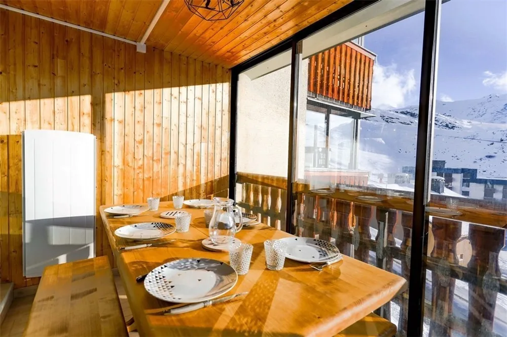 Ostakljena veranda prema jugu s blagovaonskim stolom i pogledom na planine, apartman Sérac Q4