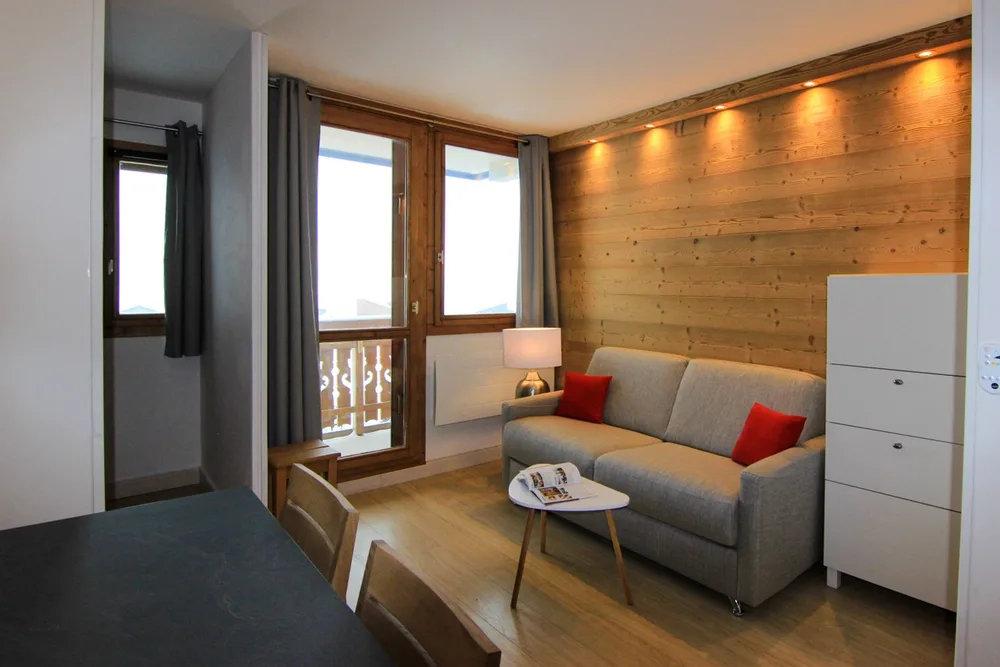 Renovirani dnevni boravak s kaučem i izlazom na balkon prema jugu, apartman Zénith 27 u Val Thorensu