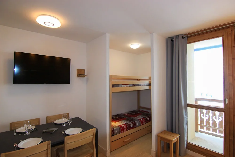 Blagovaonski stol, TV i kutak s krevetom na kat u apartmanu Zénith 27